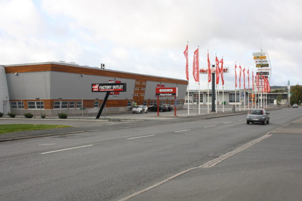 Nutida foto på en väg med industribyggnad vid kanten av vägen.