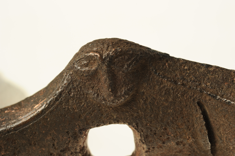 Ansiktsmask, troligen föreställande en man. Kraftigt markerade ögonbryn och näsa. Mittbenat hår.