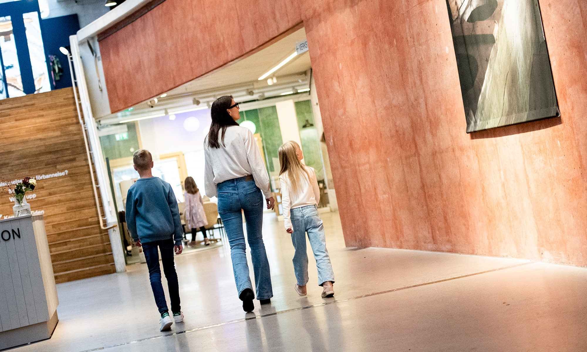 Mamma med två äldre barn går i museets entré