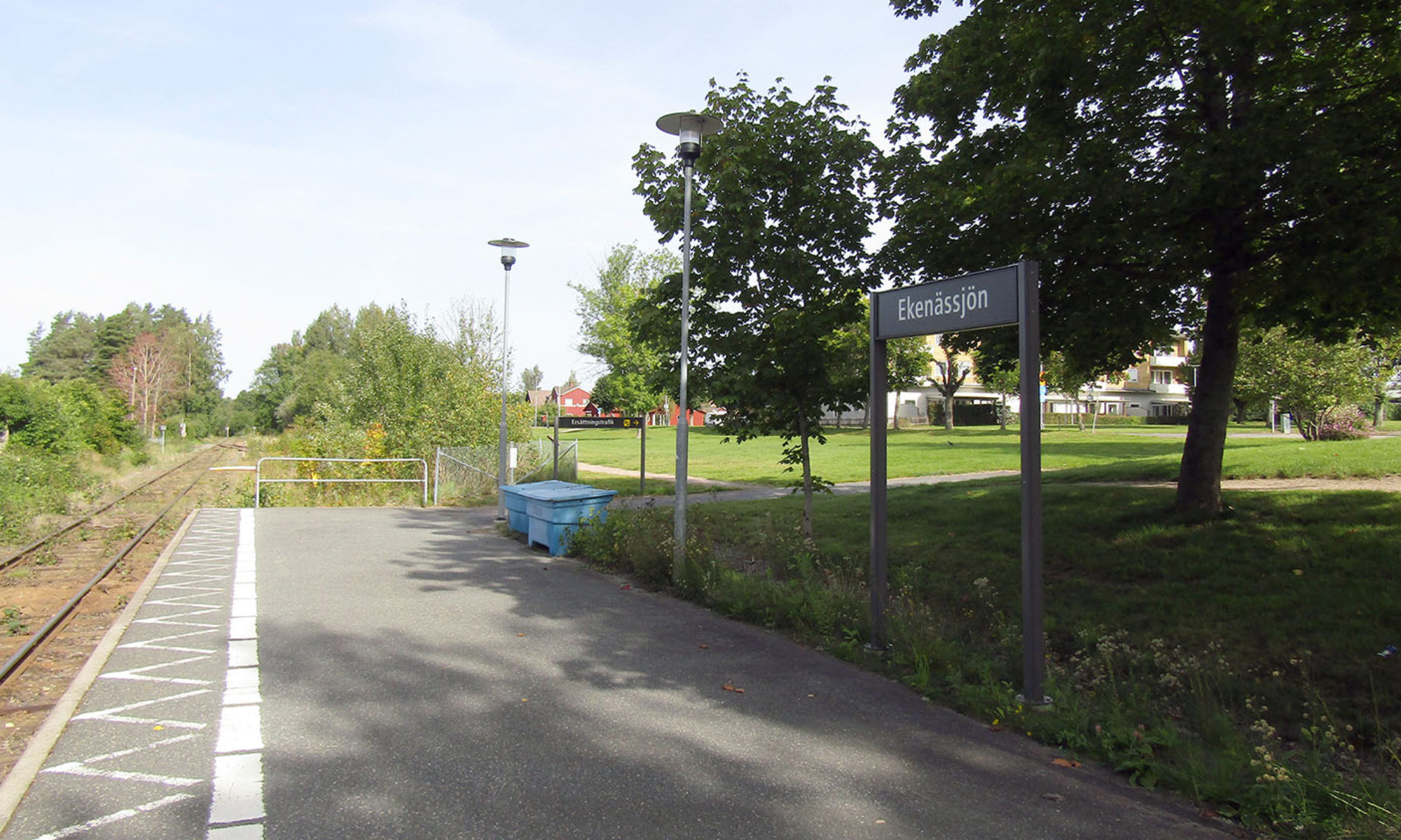 Järnvägsspår vid stationen i Ekenässjön, omgiven av grönytor och villakvarter