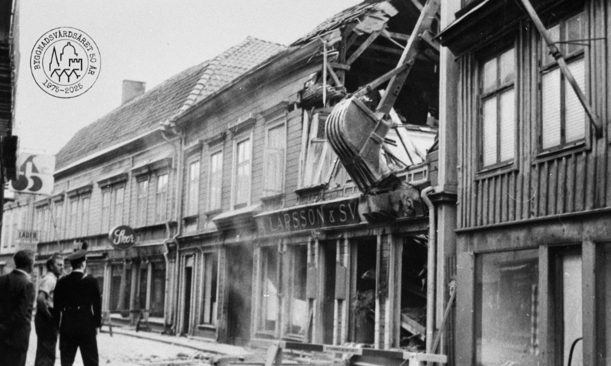 En grävmaskin river ett hus , svartvitt foto