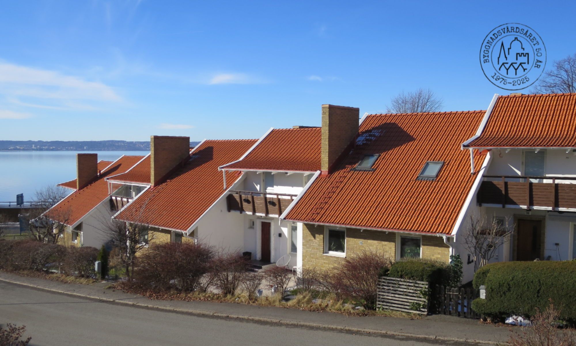 Kedjehus utmed en väg med Vättern i bakgrundn